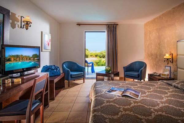Ein Hotelzimmer im Hersonissos Maris mit Fernseher, Schreibtisch, Stühlen und offenem Balkon.