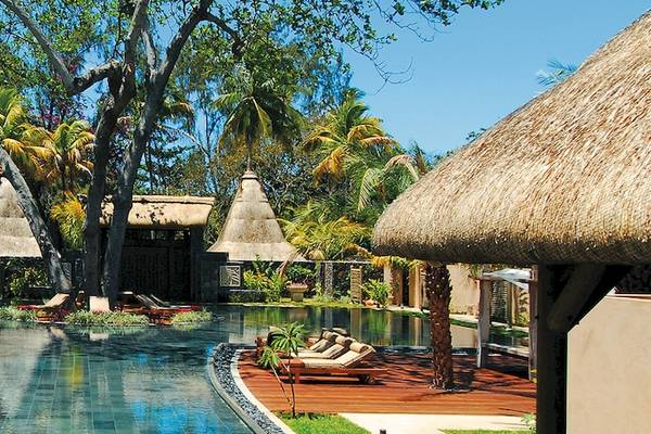 Außenbereich des Shandrani Beachcomber Resorts & Spa mit Pool, Liegestühlen und afrikanischen Dächern