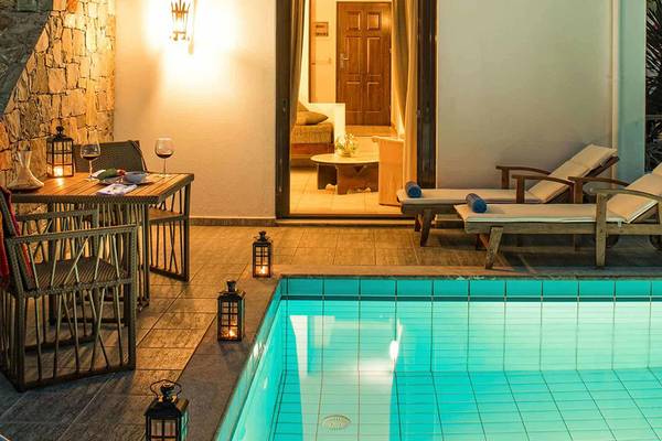 Pool-Terrasse des Hersonissos Maris Hotels mit Lounge-Sesseln und Tisch bei Nacht.