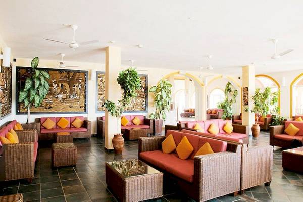 Hotellobbybereich mit Sofas, Kissen, Tischen, Pflanzen und Deckenventilatoren.