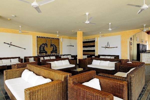 Lobby-Lounge-Bereich des Occidental Boa Vista Beach Hotels mit Korbsofas, weißen Kissen und Deckenventilatoren.