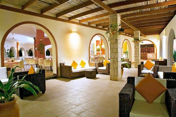 Lobby-Lounge-Bereich im Occidental Boa Vista Beach Hotel mit Sofas, Kissen und Pflanzen.