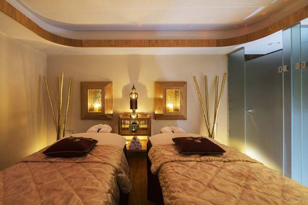 Massageraum im Pioneer Beach Hotel mit zwei Betten, goldenen Stäben und dekorativen Elementen.
