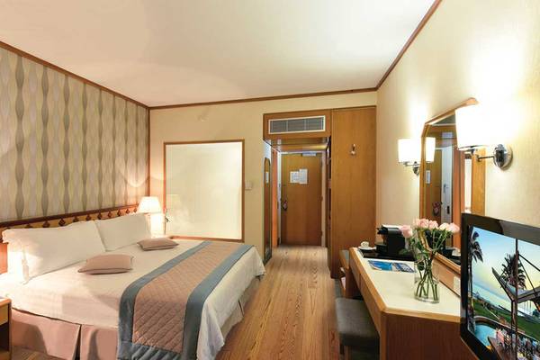 Ein geräumiges Hotelzimmer im Pioneer Beach Hotel mit einem großen Bett, einem Schreibtisch und einem Flachbildfernseher.