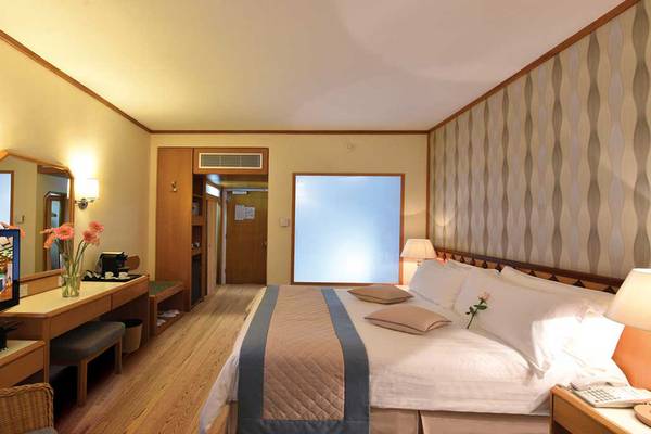 Schlafzimmer im Pioneer Beach Hotel mit Doppelbett, Fernseher, Nachttisch und Dekor.