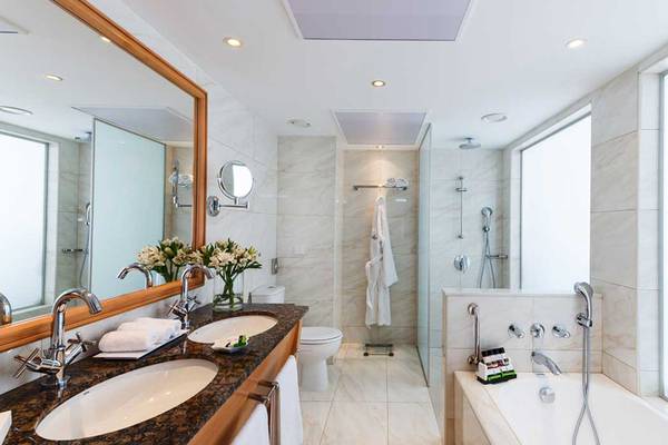 Badezimmer im Pioneer Beach Hotel mit Marmorfliesen, Doppelwaschbecken und Badewanne.