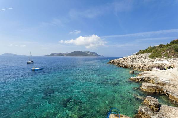 Außenbereich des Cappari Hotels Aquarius mit Blick auf das Meer und eine kleine Insel.