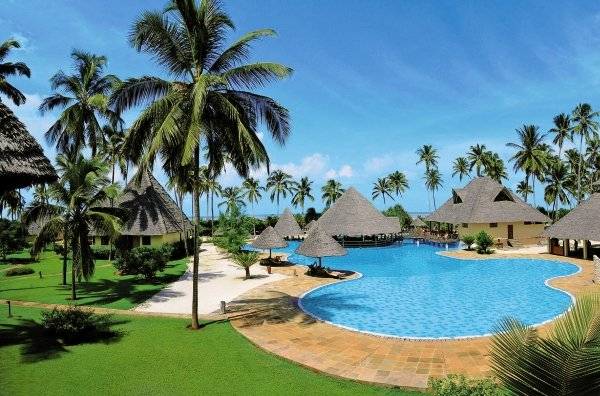 Außenbereich des Neptune Pwani Beach Resort & Spa mit Swimmingpool und umliegenden Bungalows.