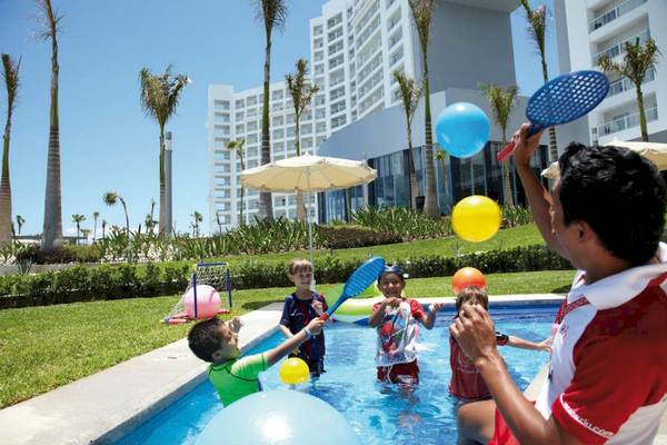 Kinder spielen mit Bällen und Spielzeug im Pool des Riu Palace Peninsula Hotels.