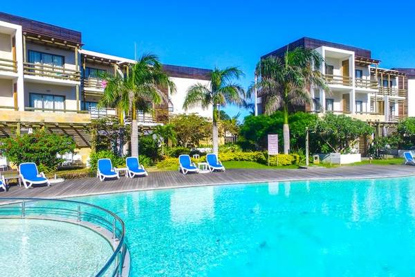 Außenpool des Anelia Resort & Spa mit Lounge-Stühlen und Gebäuden im Hintergrund.