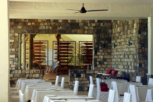 Innenbereich des Anelia Resort & Spa Restaurants mit steinerner Wand und Tischen