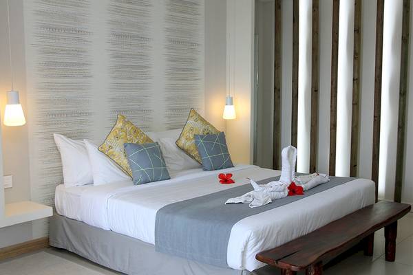 Schlafzimmer im Anelia Resort & Spa mit Bett, Kissen und roten Blumen auf der Decke.