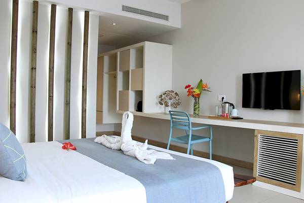 Hotelzimmer im Anelia Resort & Spa mit Bett, Schreibtisch, Fernseher und Blumenvase.