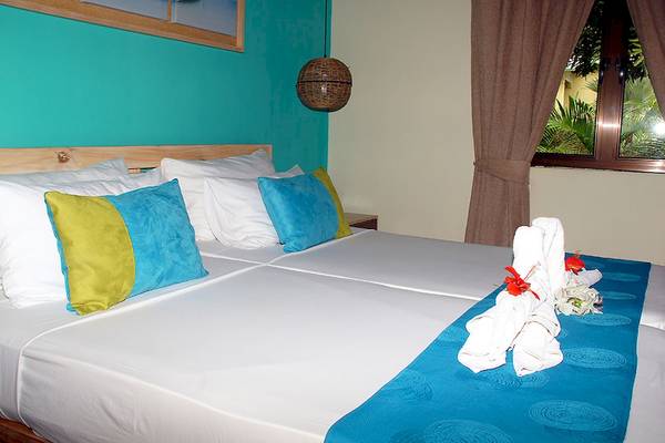 Doppelbett mit weißen Laken und blauen und grünen Kissen im Anelia Resort & Spa