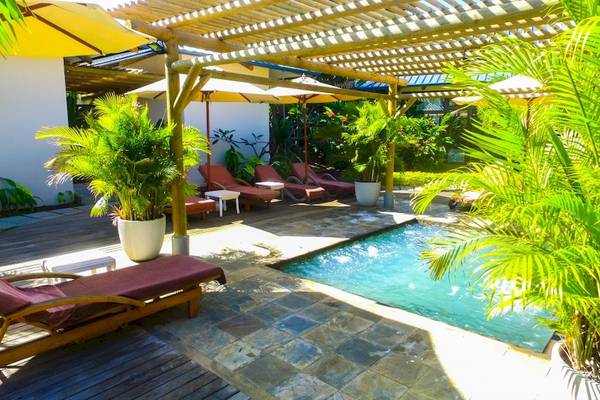 Pool-Loungebereich im Anelia Resort & Spa mit Sonnenliegen und Palmen.