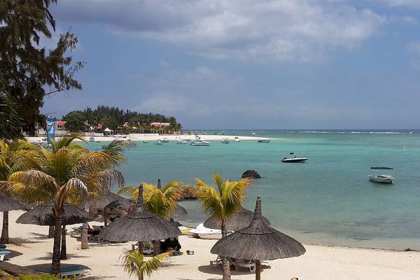 Aussicht auf den Strand des Anelia Resort & Spa mit Sonnenschirmen und Booten im Wasser.
