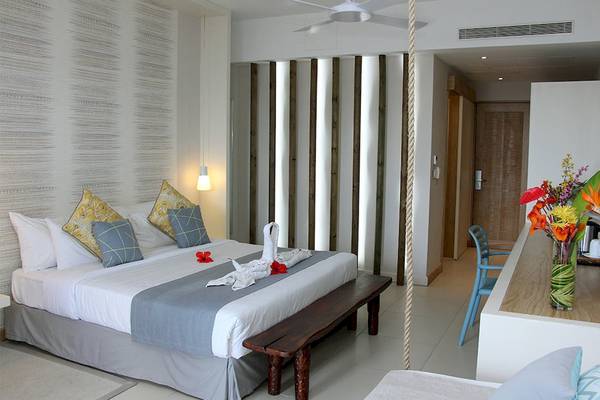 Schlafzimmer im Anelia Resort & Spa mit einem großen Bett, weichen Kissen, einem Holzbank und einem Blumenvase.