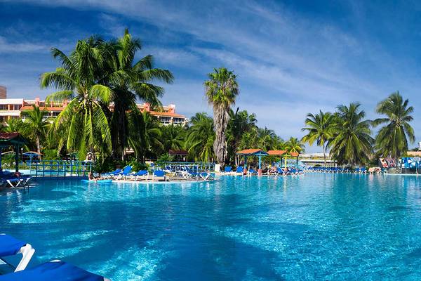 Außenpool des Occidental Arenas Blancas Hotels mit blauen Liegestühlen und Palmen