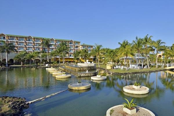 Außenbereich des Melia Las Antillas Hotels mit Teich, Palmen und Pavillon.