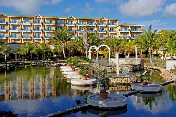 Außenansicht des Melia Las Antillas Hotels mit einem Brunnen und Palmen im Vordergrund.