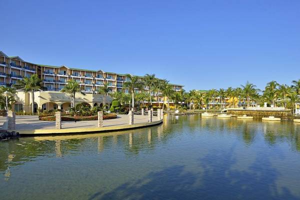 Außenansicht des Melia Las Antillas Hotels mit Wasserlandschaft und Palmen.
