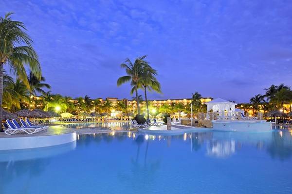 Abendansicht des Swimmingpools des Melia Las Antillas Hotels mit Liegestühlen und Palmen