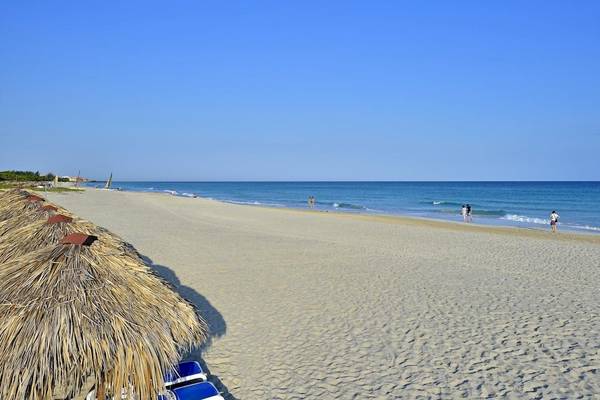Strand mit weißen Sandstränden, blauen Liegestühlen und Palmenhütten am Melia Las Antillas