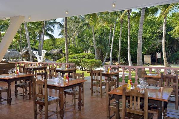 Restaurant-Terrasse im Melia Las Antillas Hotel mit Blick auf Palmen und Gebäude.