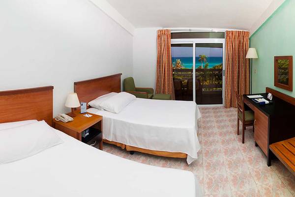 Doppelzimmer mit Meerblick im Hotel Occidental Arenas Blancas mit zwei Betten, Schreibtisch, Fernseher und Balkon.