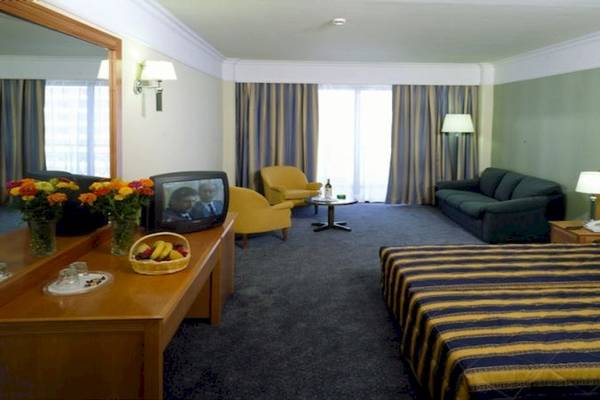 Hotelzimmer des Calypso Palace mit Bett, Fernseher, Couch, Schreibtisch und Spiegel.