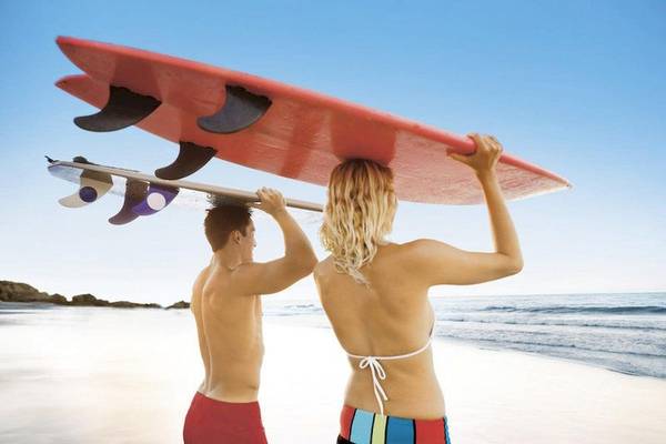 Paar am Strand mit Surfbrettern in der Hand
