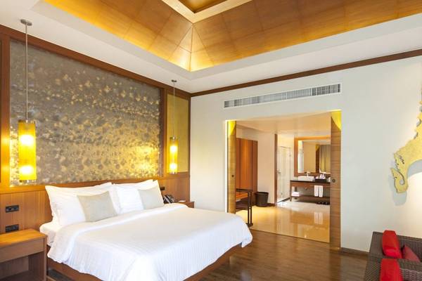 Innenansicht eines eleganten Hotelzimmers im Beyond Resort Khao Lak mit einem großen Bett, Holzboden und modernen Annehmlichkeiten.