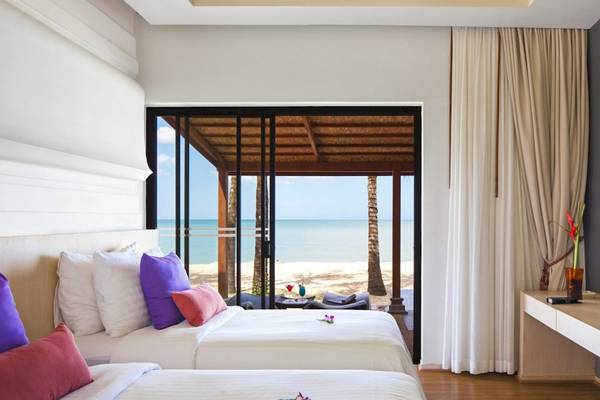 Zimmer im Beyond Resort Khao Lak mit Blick auf das Meer durch große Glastüren.
