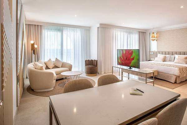 Schlafzimmer im Guayarmina Princess Hotel mit einem großen Bett, Couch, Tisch und Fernseher.
