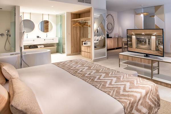 Innenansicht der Suite im Guayarmina Princess Hotel mit Bett, Fernseher und Badezimmer.