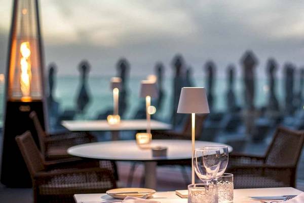 Außenbereich des Guayarmina Princess Hotels mit Tischen und Stühlen, Lampen und Blick auf das Meer.