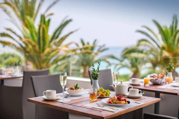 Frühstückstisch im Freien im Alion Beach Hotel mit Blick auf Palmen und Meer