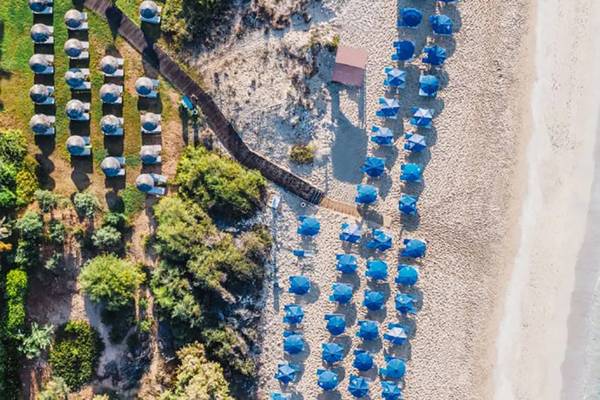 Luftaufnahme des Alion Beach Hotels, Strand mit blauen Sonnenschirmen und kristallklarem Wasser