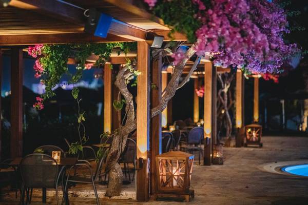 Außenbereich des Alion Beach Hotel bei Nacht mit beleuchteten Tischen und Stühlen.
