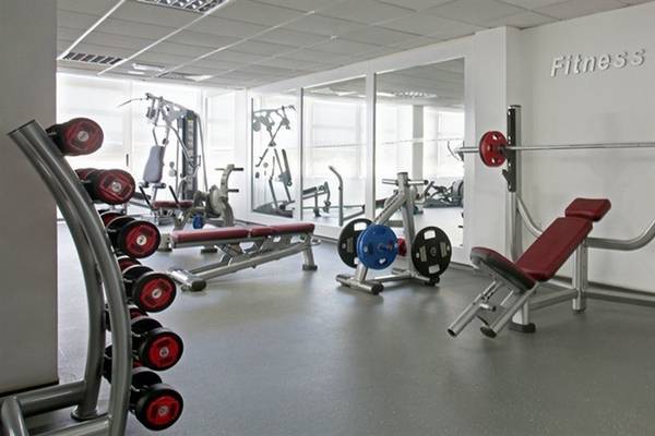 Fitnessstudio im Alion Beach Hotel mit verschiedenen Geräten und einer weißen Wand.