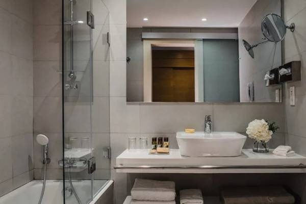 Modernes Badezimmer im Alion Beach Hotel mit Badewanne, Waschbecken und Glasdusche