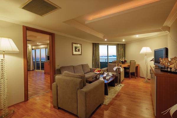 Wohnzimmer des Crystal Admiral Resort Suites & Spa mit moderner Einrichtung, einem großen Fenster und Blick auf den Ozean.