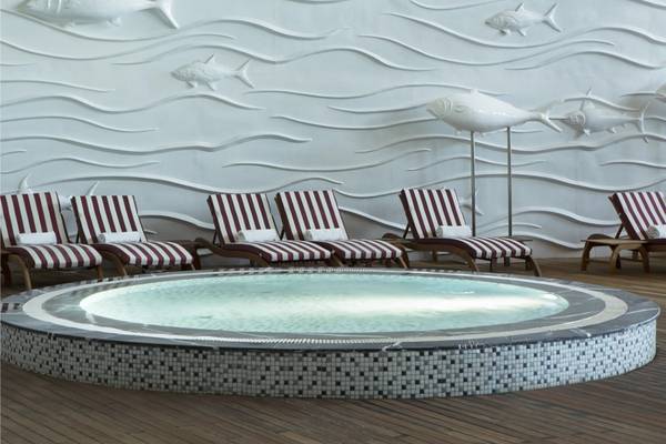 Pool-Loungebereich im Maxx Royal Belek Golf Resort mit weißen Fischen an der Wand