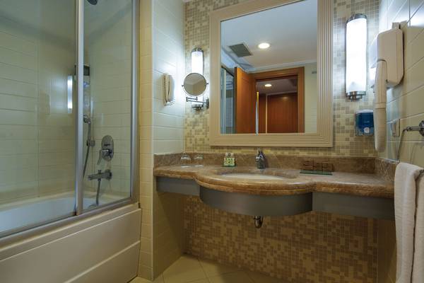Badezimmer im Crystal Admiral Resort Suites & Spa mit Dusche, Spiegel und Waschbecken.