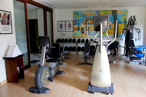 Fitnessraum im Mai Samui Beach Resort & Spa mit Trainingsgeräten und einer Wandmalerei.