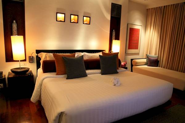 Schlafzimmer im Mai Samui Beach Resort & Spa mit Bett, Kissen, Nachttischen und Lampen