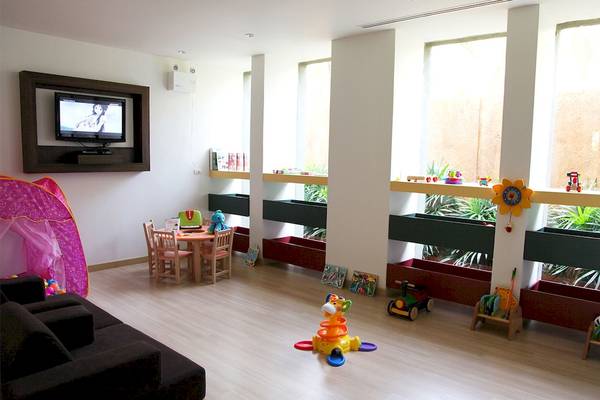 Kinderzimmer im Mai Samui Beach Resort & Spa mit Fernseher, Tisch, Stühlen und Spielzeug.