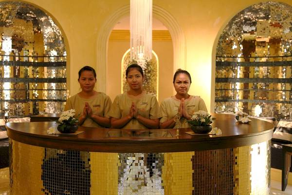 Drei Mitarbeiter im Mai Samui Beach Resort & Spa vor einem goldenen Empfangstresen.