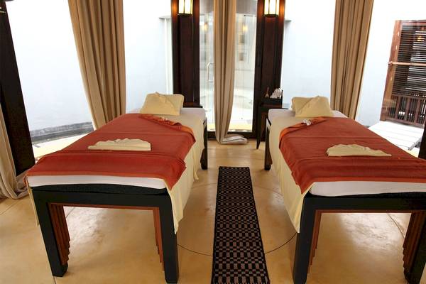 Zwei Massageliegen im Mai Samui Beach Resort & Spa mit roten Decken und gelben Kissen.