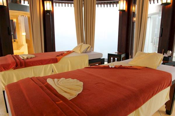 Massageraum im Mai Samui Beach Resort & Spa mit zwei Betten und gelben Kissen.